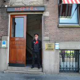 Portier Nico staat in de deuropening van Hotel New York Rotterdam